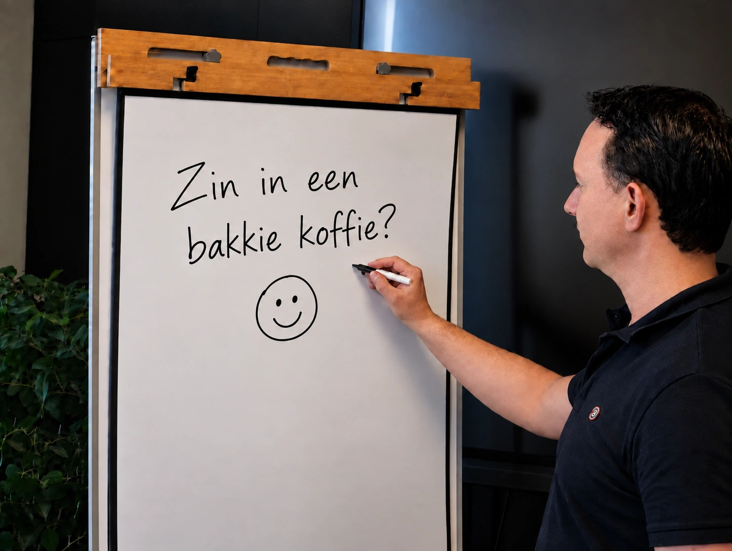 Pascal bij het whiteboard met de tekst 'Zin in een bakkie koffie?' en een handgetekende smiley